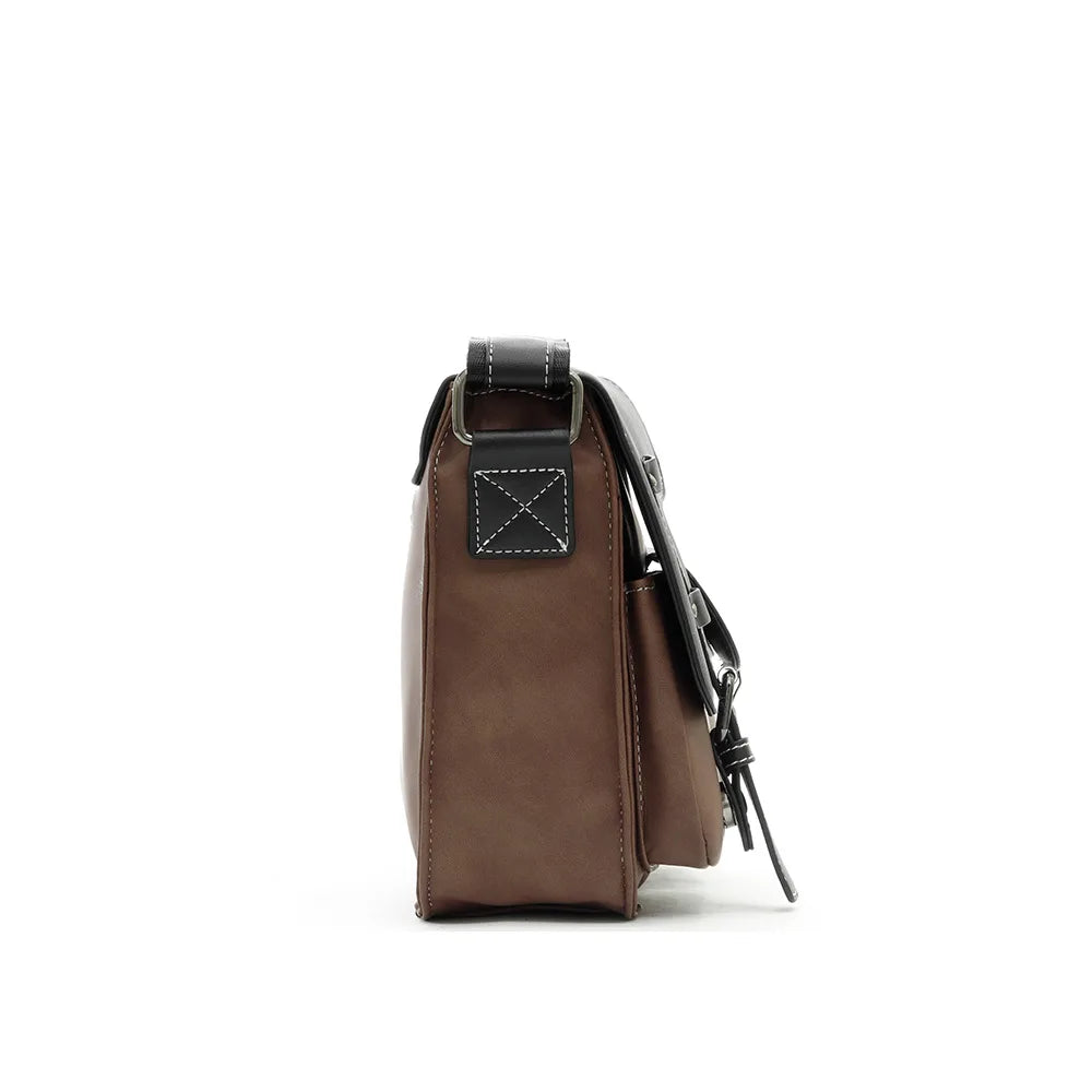 Borsa a tracolla in pelle marrone, vista laterale, con cuciture bianche e chiusura a fibbia. Accessorio moda elegante e versatile per uomo e donna.