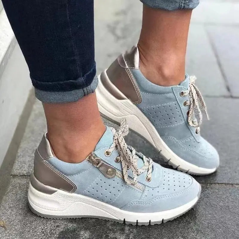Scarpe da ginnastica donna, colore azzurro e bianco, suola spessa, lacci bianchi, design casual sportivo, indossate su pavimento grigio.