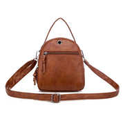 Zaino in pelle marrone da donna con tasca frontale con zip, tracolla regolabile e manico superiore. Elegante e pratico per l'uso quotidiano.