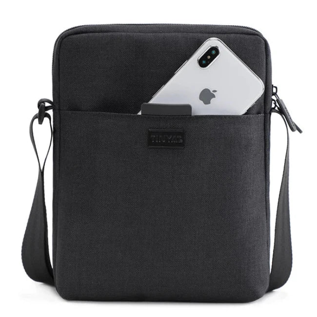 Borsa a tracolla nera con tasca frontale contenente uno smartphone. Design elegante, ideale per uomo e donna. Accessorio moda pratico e versatile.