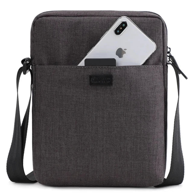 Borsa a tracolla in tessuto grigio scuro con tasca frontale, contenente uno smartphone. Design elegante e pratico per uomo e donna.