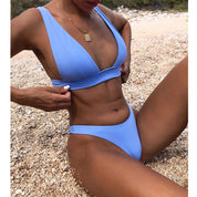 Donna in bikini azzurro su spiaggia di ciottoli, costume da bagno estivo, moda mare, abbigliamento da spiaggia, relax al sole, vacanza estiva.