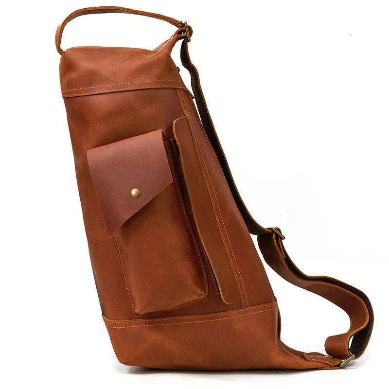 Zaino monospalla in pelle marrone, design elegante e funzionale, con tasca frontale con bottone. Ideale per viaggi e uso quotidiano.