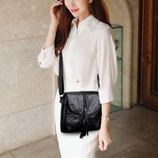 Donna con borsa a tracolla nera in pelle, abito bianco elegante. Accessorio moda femminile, stile casual chic. Perfetta per ogni occasione.