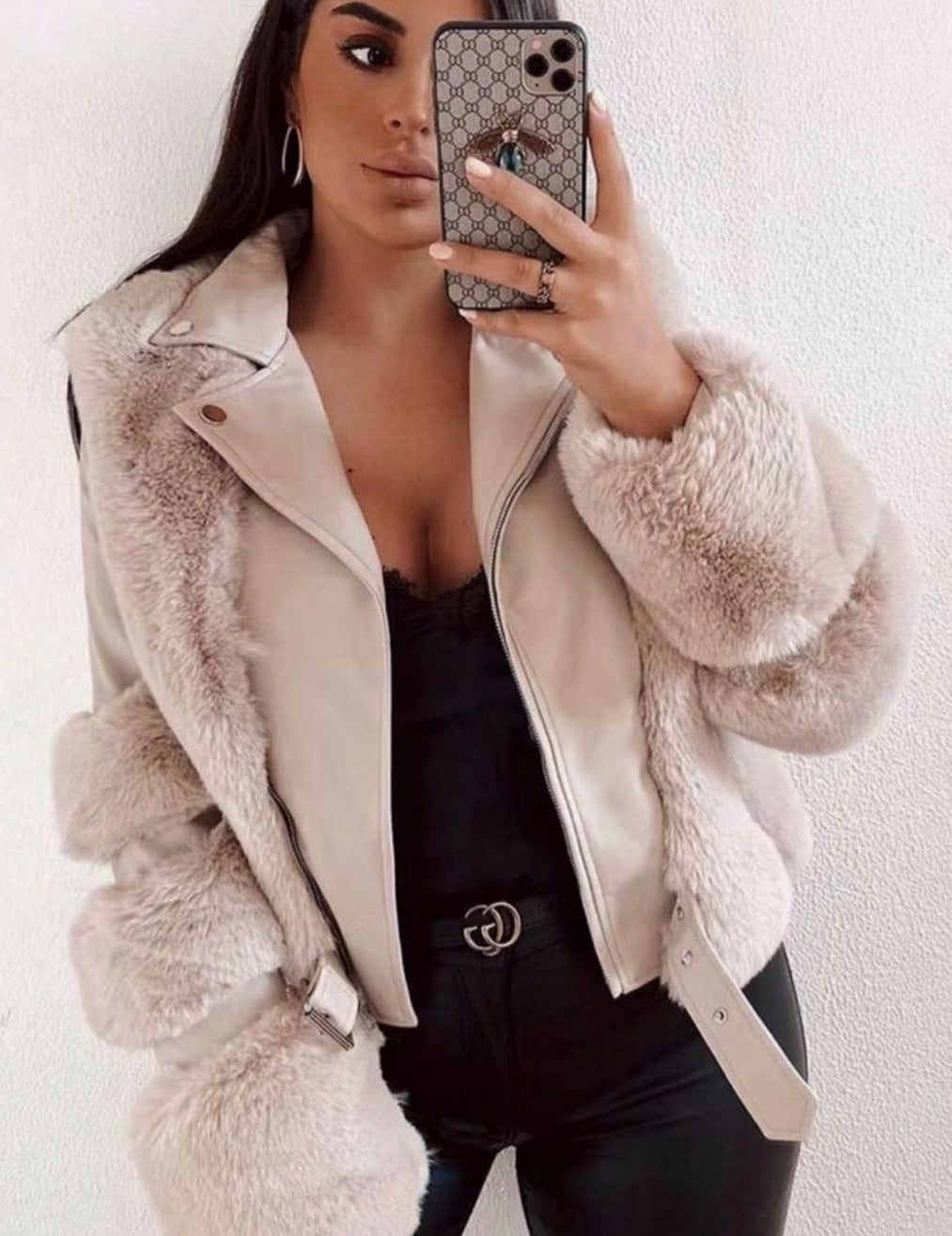 Donna con giacca in ecopelliccia beige, pantaloni neri, top nero, e smartphone. Moda autunno inverno, abbigliamento elegante e trendy.