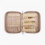 Custodia portagioie da viaggio aperta in pelle beige con scomparti per collane, orecchini e anelli. Organizzatore compatto per gioielli.