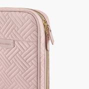 Custodia laptop rosa trapuntata con motivo a spina di pesce, cerniera dorata e marchio visibile. Accessorio elegante e protettivo per computer portatile.
