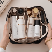 Borsa cosmetica aperta con flaconi di skincare e trucco, pennelli e accessori. Organizzazione prodotti bellezza, viaggio, cura personale.