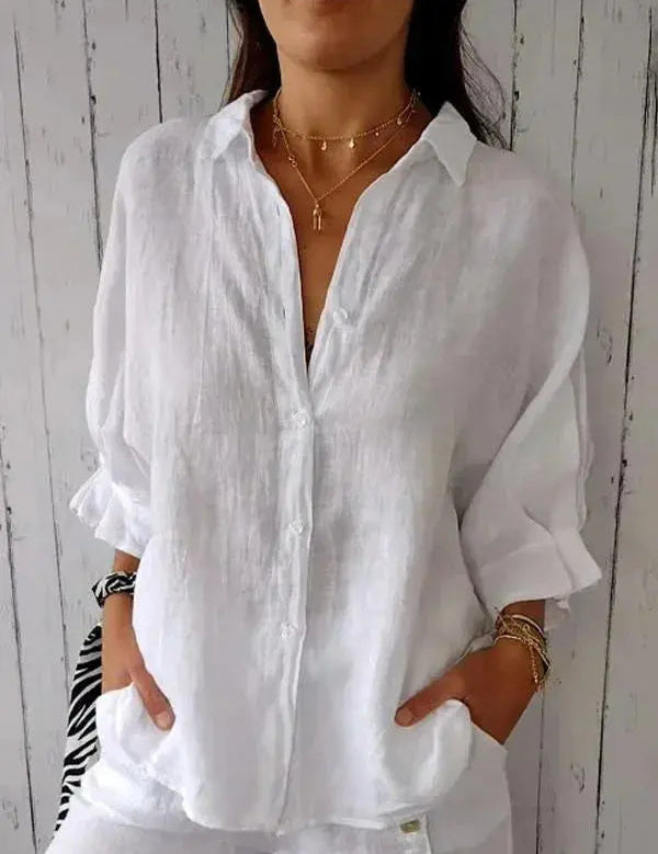 Camicia bianca in lino da donna, maniche lunghe, stile casual, abbinata a collane dorate. Elegante e leggera, perfetta per l'estate.
