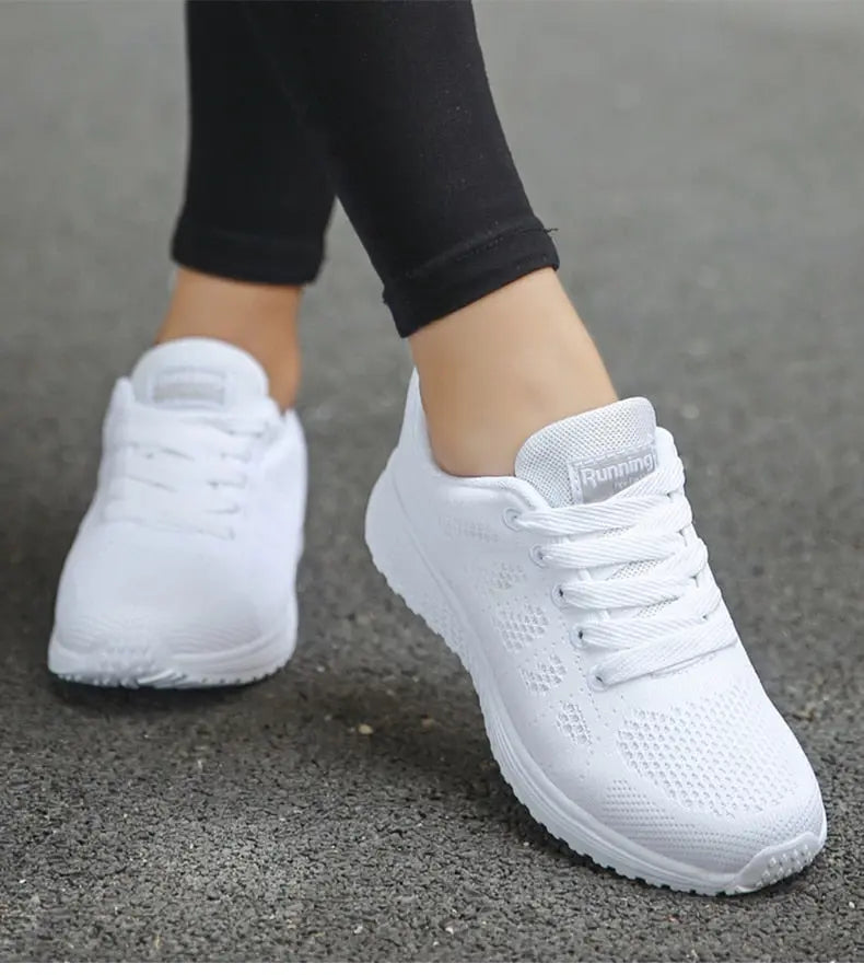 Scarpe da corsa bianche da donna su strada asfaltata, design traspirante, suola antiscivolo, ideali per jogging e attività sportive all'aperto.