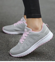 Scarpe da ginnastica grigie da donna con lacci rosa, suola bianca antiscivolo, design traspirante, ideali per corsa e fitness su strada asfaltata.