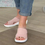 Sandali rosa da donna con suola bianca, indossati con jeans arrotolati. Scarpe estive comode, ideali per passeggiate e look casual.
