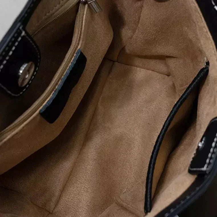Interno borsa in pelle nera, foderata in tessuto beige, con tasca con zip e chiusura magnetica. Accessorio moda donna elegante e spazioso.