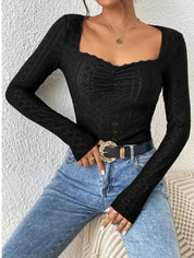 Donna con top nero a maniche lunghe e jeans blu, cintura con fibbia dorata. Moda casual elegante, abbigliamento femminile trendy.