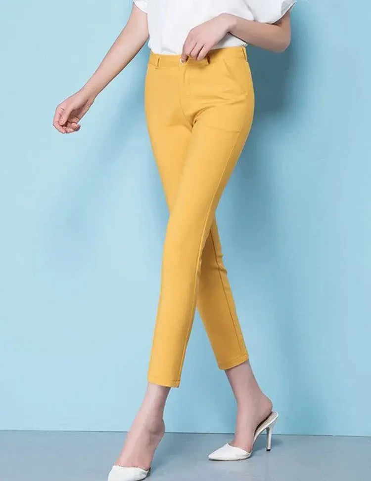 Pantaloni gialli da donna, eleganti e aderenti, abbinati a scarpe bianche con tacco. Ideali per look casual e formali.
