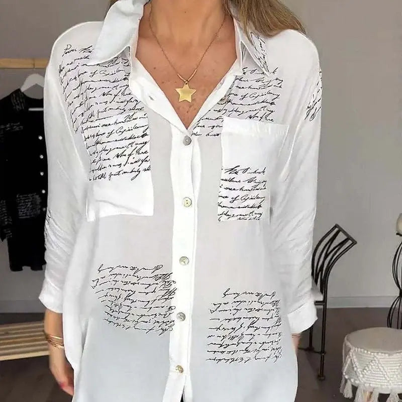Camicia bianca da donna con scritte nere, maniche lunghe, colletto classico e tasca frontale. Elegante e casual, perfetta per ogni occasione.