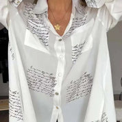 Camicia bianca da donna con stampa calligrafica nera, colletto classico e bottoni. Moda elegante, abbigliamento casual, tendenza 2023.