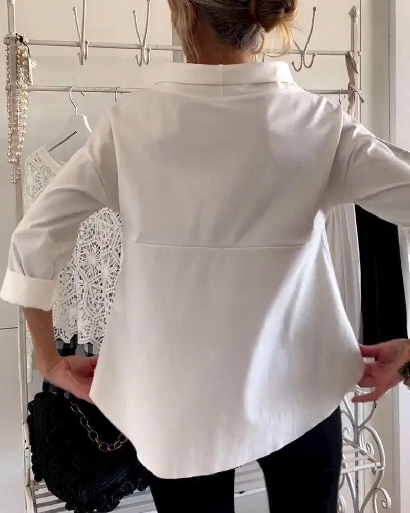 Camicia bianca elegante da donna, maniche lunghe, indossata da una persona di spalle. Sfondo con abiti appesi. Moda femminile, abbigliamento casual.