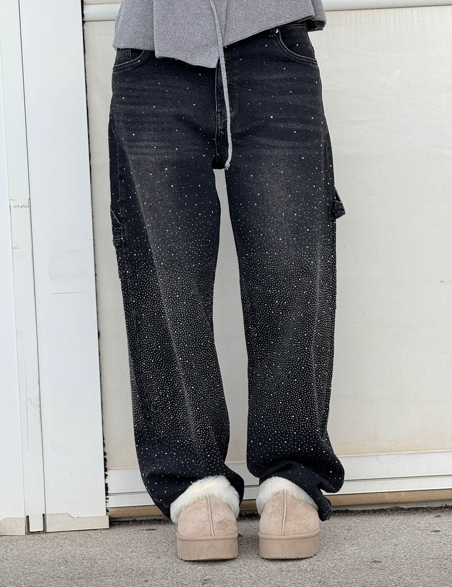 Jeans neri con dettagli glitterati, indossati con scarpe beige invernali. Moda casual, pantaloni decorati, stile urbano.