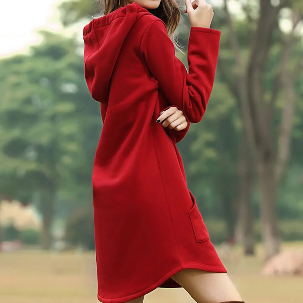 Donna con abito rosso con cappuccio in un parco verde. Moda autunnale, vestito casual, abbigliamento femminile elegante.