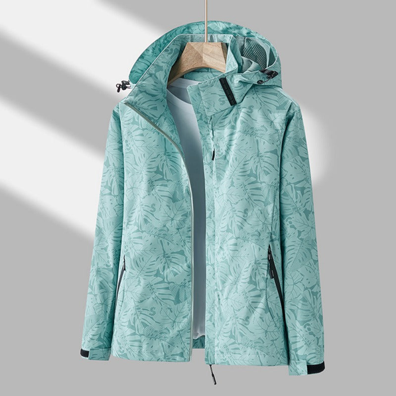 Giacca impermeabile donna verde menta con cappuccio, motivo foglie, chiusura zip, tasche laterali, ideale per escursioni e attività outdoor.