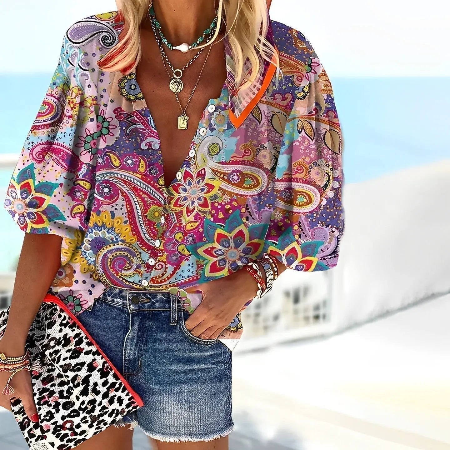 Blusa colorata a fantasia paisley, indossata con shorts di jeans e accessori moda. Look estivo vivace e trendy per donna.