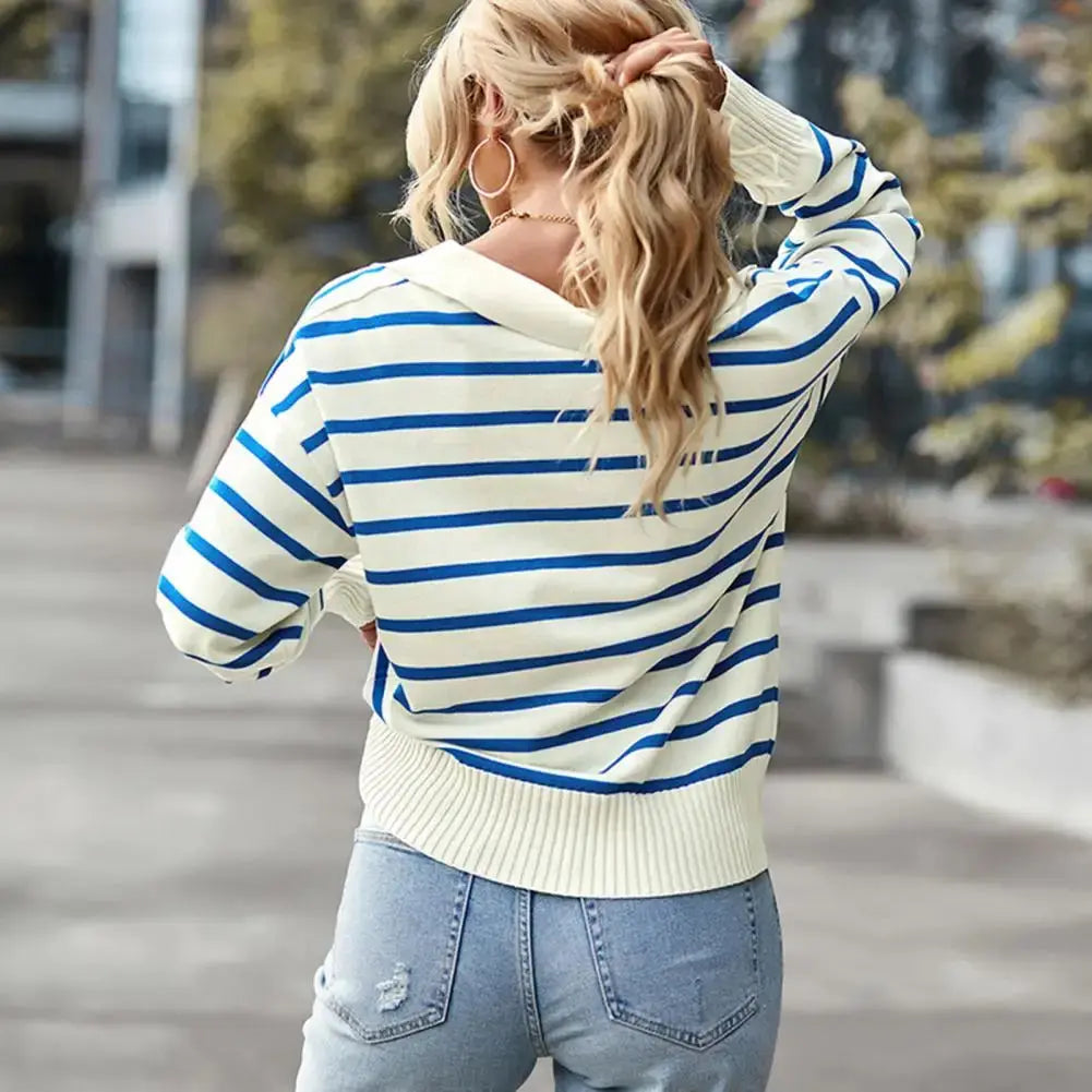Maglione a righe blu e bianche, donna di spalle, jeans chiari, capelli biondi ondulati, moda casual autunnale, strada urbana.
