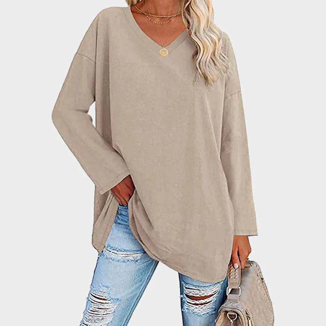 Maglia oversize beige donna, maniche lunghe, scollo a V, abbinata a jeans strappati. Look casual moda autunno.