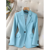 Giacca blazer donna azzurra elegante su sedia beige, con bottoni neri e tasche, ideale per abbigliamento formale e moda ufficio.