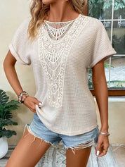 Donna con maglietta beige in pizzo e shorts di jeans, posa casual in interni. Moda estiva, abbigliamento femminile, stile boho chic.