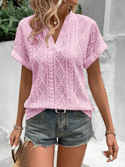 Donna con maglia rosa traforata e pantaloncini di jeans, accessoriata con borsa di paglia. Look estivo casual, moda femminile trendy.