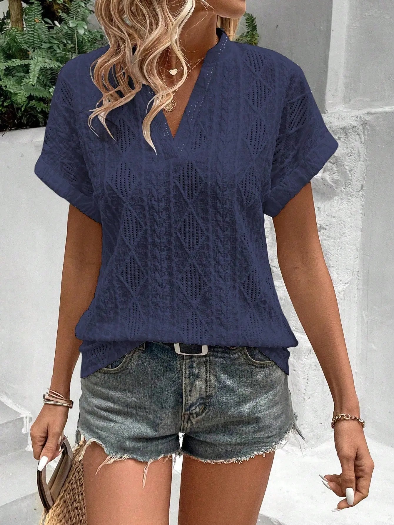 Blusa blu traforata da donna, maniche corte, abbinata a shorts di jeans. Look estivo casual, moda femminile, outfit trendy per il tempo libero.