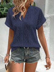 Blusa blu traforata da donna, maniche corte, abbinata a shorts di jeans. Look estivo casual, moda femminile, outfit trendy per il tempo libero.