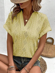 Blusa estiva gialla traforata con motivo geometrico, indossata da donna con cappello di paglia. Look casual, perfetto per la moda estiva.
