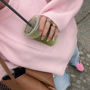 Maglione rosa oversize, jeans chiari, scarpe rosa, borsa marrone, bevanda verde in mano con cannuccia nera. Look casual e trendy.