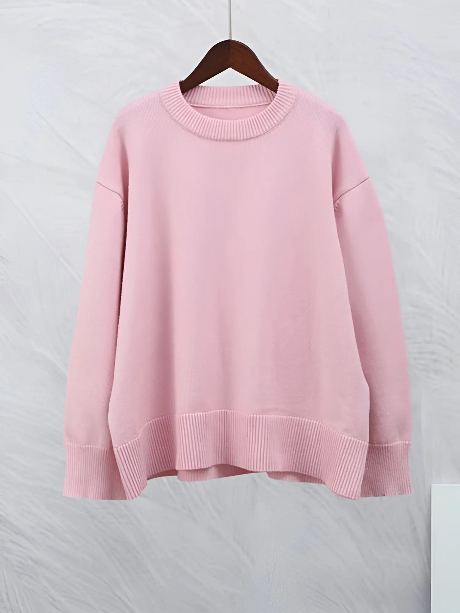 Maglione rosa pastello in cotone, girocollo, maniche lunghe, design casual, appeso su gruccia. Moda donna, abbigliamento autunnale.