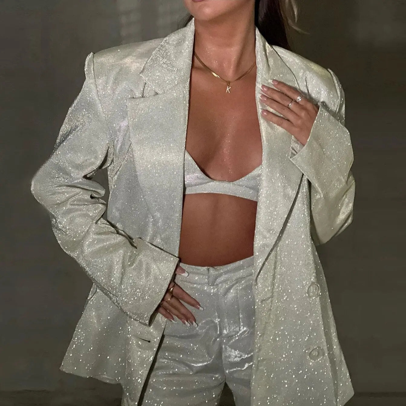 Giacca e pantaloni scintillanti donna, abbinati a top corto, moda elegante, tessuto luccicante, abbigliamento da sera glamour, stile moderno.