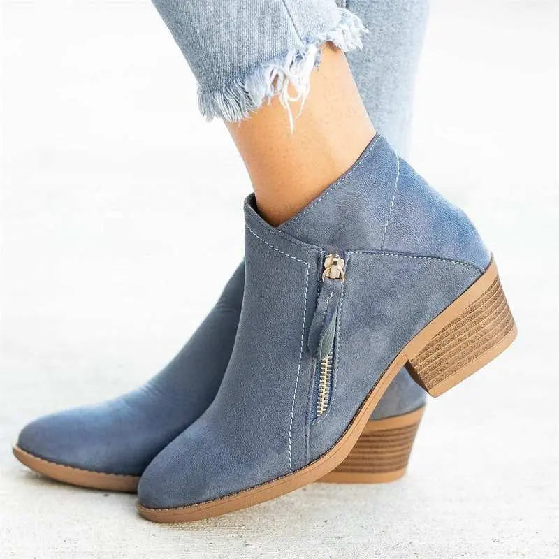 Stivaletti donna in camoscio blu con tacco basso e zip laterale, abbinati a jeans chiari. Scarpe moda autunno, comode e eleganti.