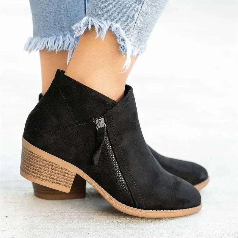 Stivaletti neri in camoscio con tacco basso, zip laterale, indossati con jeans strappati. Scarpe moda donna, eleganti e casual.