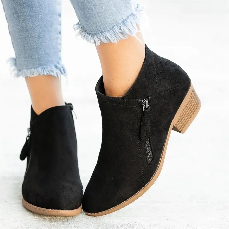 Stivaletti neri in camoscio con tacco basso, zip laterale, indossati con jeans chiari. Scarpe moda donna, eleganti e casual.