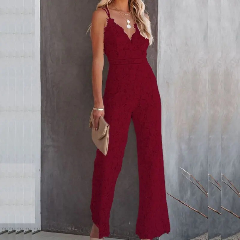 Donna in elegante tuta rossa in pizzo, con scollo a V e pantaloni larghi, accessoriata con collana e borsa beige. Moda femminile, abbigliamento serale.