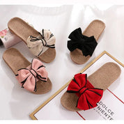 Quattro paia di ciabatte estive in paglia con fiocco colorato: beige, nero, rosa e rosso. Design elegante, perfette per la moda estiva.