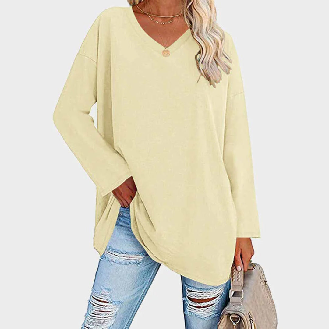 Maglia oversize gialla a maniche lunghe, scollo a V, abbinata a jeans strappati e borsa beige. Moda casual donna, look autunnale.