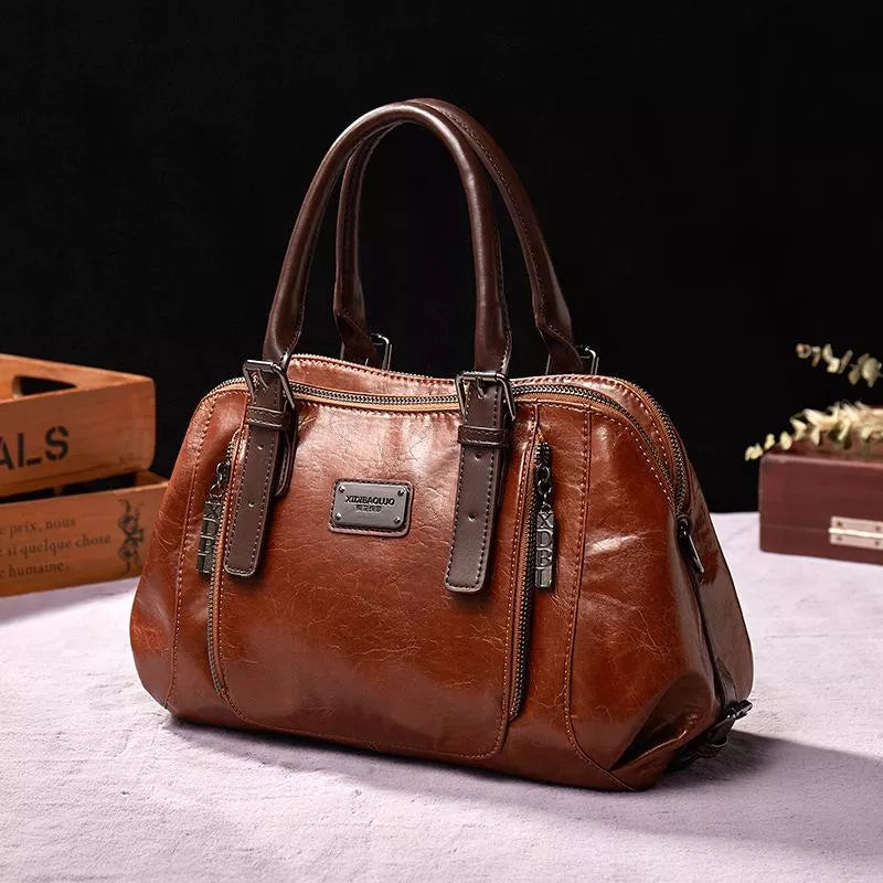 Borsa a mano in pelle marrone, design elegante con doppie maniglie, cerniere metalliche e dettagli raffinati. Accessorio moda donna di alta qualità.