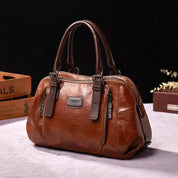 Borsa a mano in pelle marrone, design elegante con doppie maniglie, cerniere metalliche e dettagli raffinati. Accessorio moda donna di alta qualità.