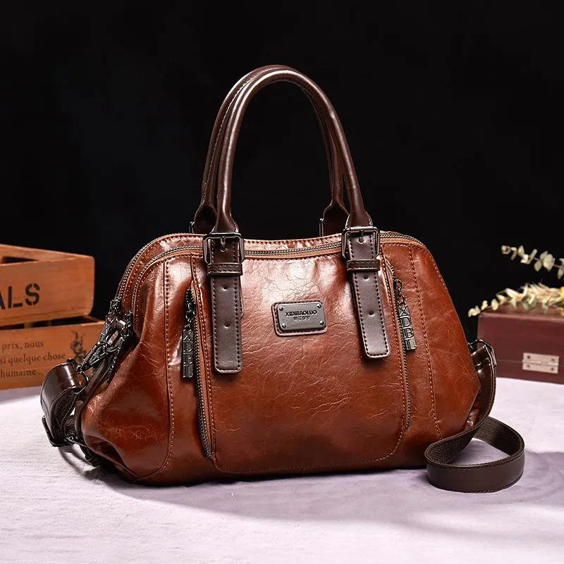 Borsa a mano in pelle marrone, design elegante con doppie maniglie, cerniere decorative e dettagli in metallo. Accessorio moda donna di lusso.