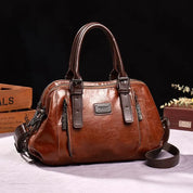 Borsa a mano in pelle marrone, design elegante con doppie maniglie, cerniere decorative e dettagli in metallo. Accessorio moda donna di lusso.
