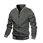 Giacca bomber grigia da uomo, con zip frontale, polsini e colletto a righe bianche e rosse. Stile casual, ideale per moda autunnale.