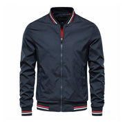 Giacca bomber blu scuro da uomo, con zip frontale, colletto e polsini a righe rosse e bianche. Stile casual, ideale per moda autunnale.