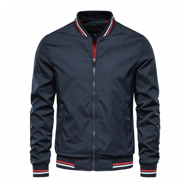 Giacca bomber blu scuro da uomo, con zip frontale, colletto e polsini a righe rosse e bianche. Stile casual, ideale per moda autunnale.